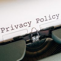 安全合规编辑周默在显示器前检查页面安全提示与投诉邮件，桌面整洁只有笔记本与一杯茶
